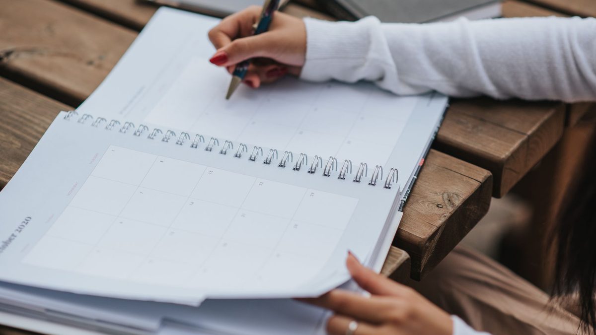 A blank weekly planner grid on a desk with highlighters and course booklets